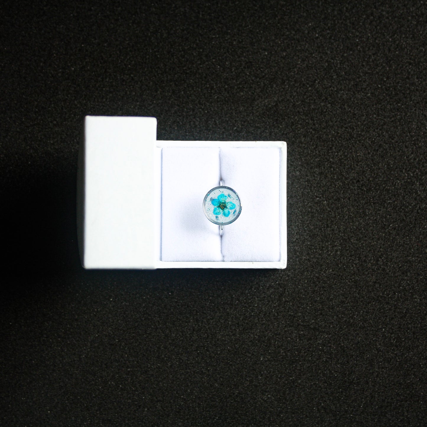 Bague fond blanc fleur séchée bleue